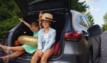 little sisters sitting in trunk waiting for charging car before travelling