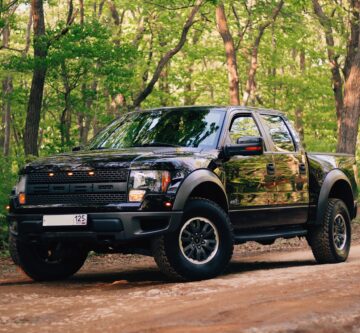 black ford ranger in the forest on a dirt track with trees all around