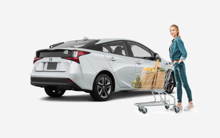 woman standing in front of white Toyota Prius after grocery shopping