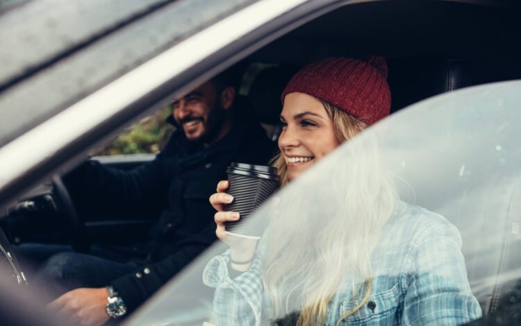 smiling woman having a coffee with man driving the car