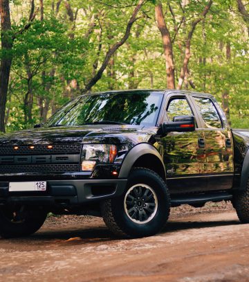 black ford ranger in the forest on a dirt track with trees all around