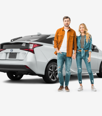 young couple standing in front of white toyota prius