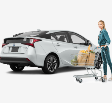 woman standing in front of white Toyota Prius after grocery shopping