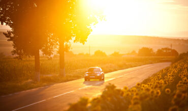 BMW M3 car drives through a beautiful scenery at sunset