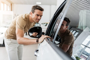 smiling man expressing concernment while looking at passenger compartment through window of a car