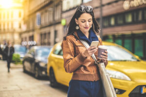 woman on phone with a coffee cup walking in the city