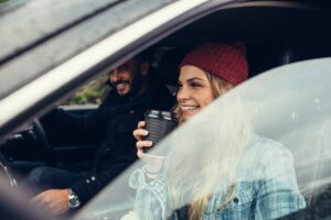 smiling woman having a coffee with man driving the car