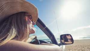 young woman driving a car on the beach