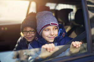 young boys driven school by car on a old autumn day and looking out the window