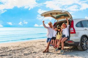 young family sitting in the back of a white SUV on the beach