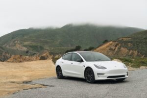 White Tesla Model 3 in the outback showing mountains and dirt road