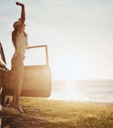 young woman enjoying a road trip along the coast