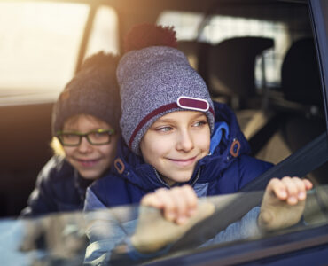 young boys driven school by car on a old autumn day and looking out the window