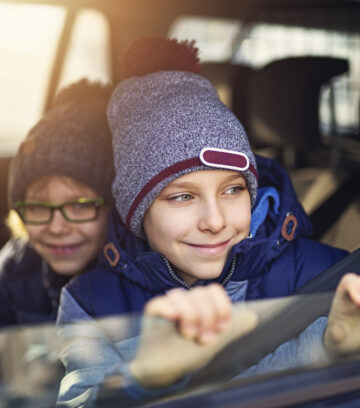 young boys driven school by car on a old autumn day and looking out the window