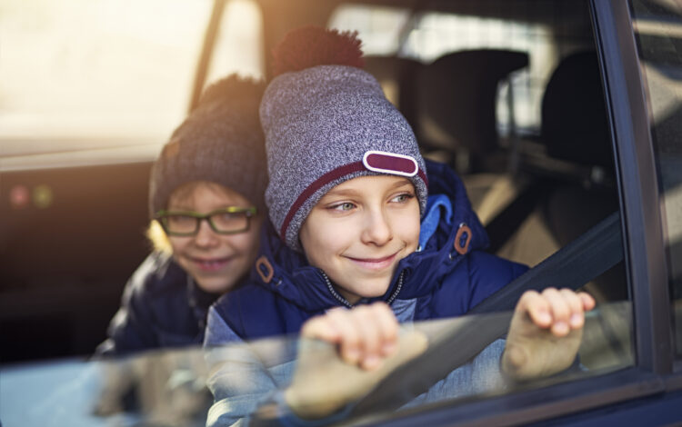 young boys driven school by car on a old autumn day and looking out the window