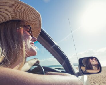 young woman driving a car on the beach