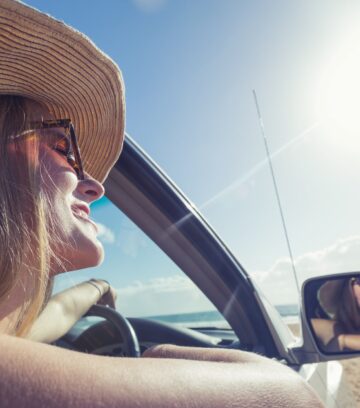 young woman driving a car on the beach