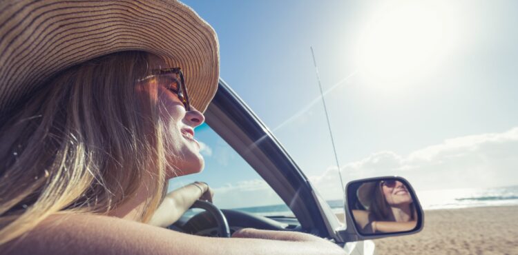 young woman driving a car on the beach