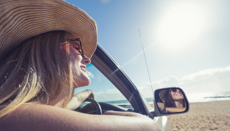 young woman driving a car on the beach