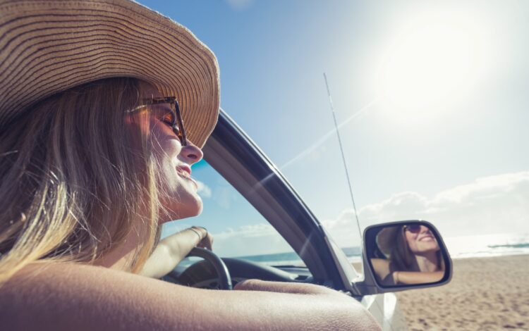 young woman driving a car on the beach