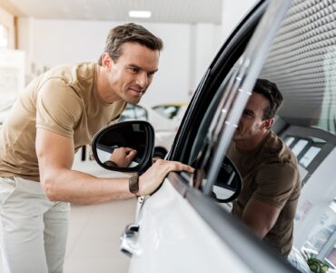 smiling man expressing concernment while looking at passenger compartment through window of a car