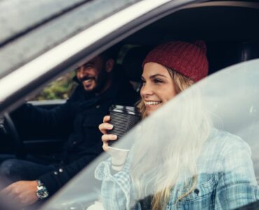 smiling woman having a coffee with man driving the car