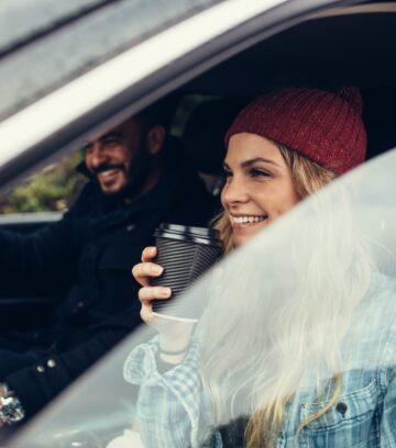 smiling woman having a coffee with man driving the car