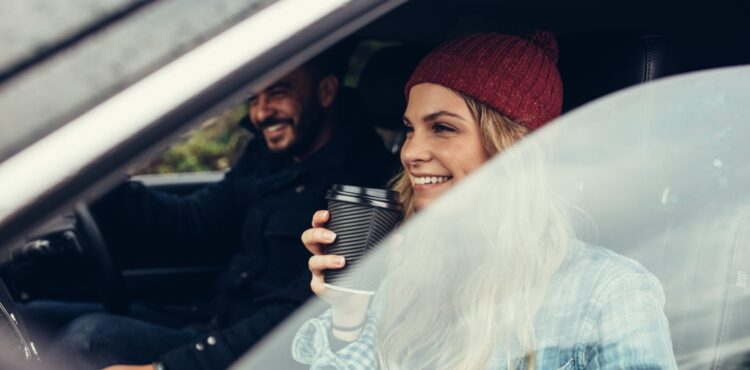 smiling woman having a coffee with man driving the car