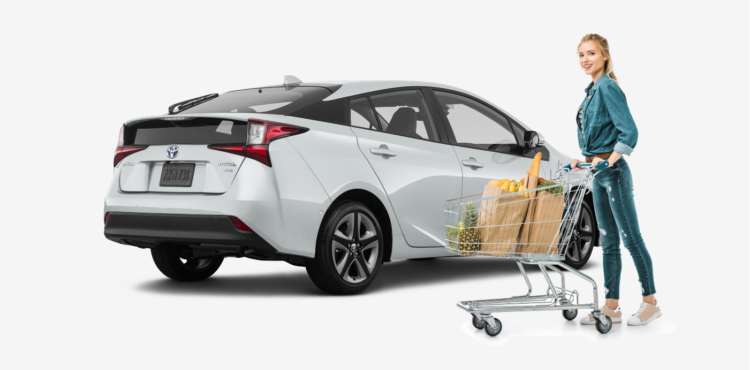 woman standing in front of white Toyota Prius after grocery shopping