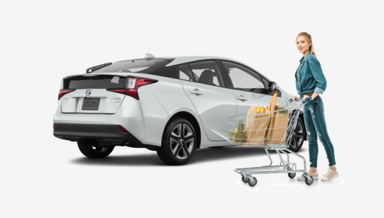 woman standing in front of white Toyota Prius after grocery shopping