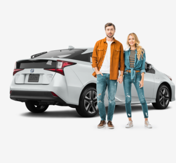 young couple standing in front of white toyota prius