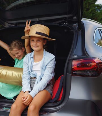 little sisters sitting in trunk waiting for charging car before travelling