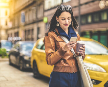 woman on phone with a coffee cup walking in the city