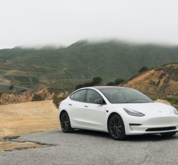 White Tesla Model 3 in the outback showing mountains and dirt road