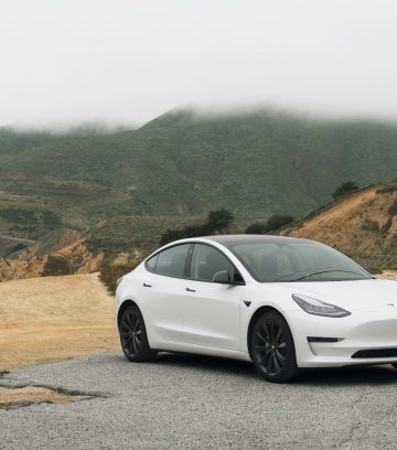 White Tesla Model 3 in the outback showing mountains and dirt road